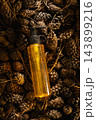 Yellow cosmetic dispenser bottle with water drops lying on natural brown pine cones background 143899216