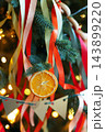 Vertical close-up of a dried orange slice ornament with festive ribbons on a Christmas tree 143899220