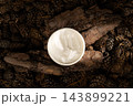 Top view of open cosmetic jar with white cream placed on natural tree bark and pine cones 143899221