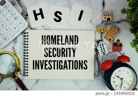 HSI Homeland Security Investigations text written on notepad with house model, calculator, magnifying glass and alarm clock on marble background 143900028