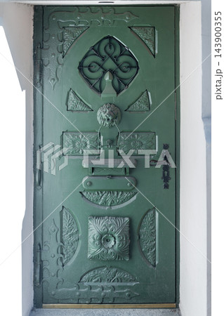 Ornate green door with lion knocker on a historic building facade 143900355