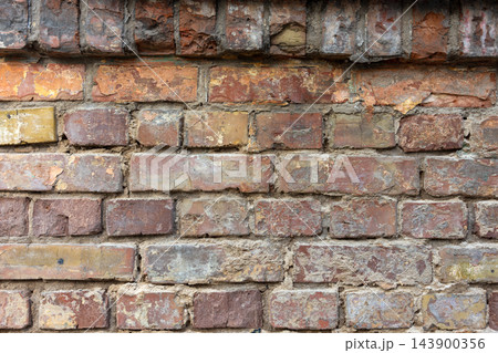 Weathered brick wall shows peeling paint and aged industrial texture 143900356