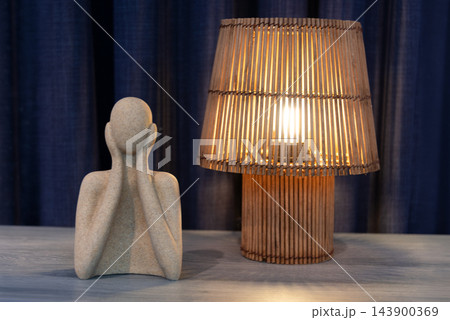 Abstract sculpture and wooden lamp illuminate a minimalist interior table 143900369