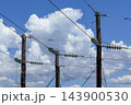 Wooden telephone poles set against a vibrant cloudy blue sky 143900530