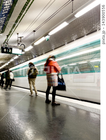 Paris Metro train arriving at a station, captured with intentional motion blur as an artistic photographic technique, creating dynamic light trails and a sense of movement on the platform. High 143900556
