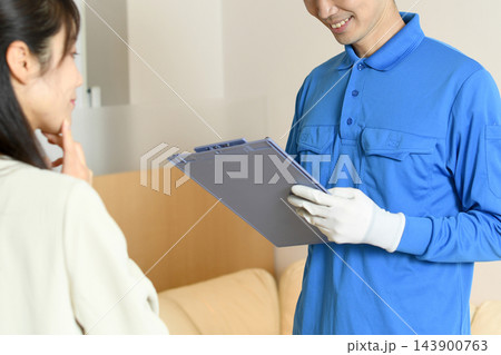 出張買取の見積もりを説明する作業員と女性 143900763