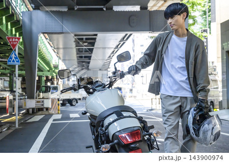 新橋の高架下で大型バイクを押して歩く若い男性ライダー 新橋の高架下で大型バイクを押して歩く若い男性ライダー 143900974