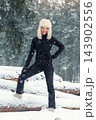 Portrait young adult mid age smile woman enjoy have fun walking in park forest snowfall cold winter day. Female portrait person happiness wear black ski overall stylish fur hat snowflakes background 143902556