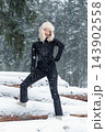 Portrait young adult mid age smile woman enjoy have fun walking in park forest snowfall cold winter day. Female portrait person happiness wear black ski overall stylish fur hat snowflakes background 143902558