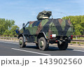 German military truck camouflage drives along autobahn green forest landscape during summer daylight. Tactical transport vehicle logistic defense mobility convoy movement European road infrastructure 143902560