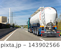 White big modern tanker shipment cargo commercial semi trailer truck moving fast on motorway road city urban suburb. Business distribution logistics service. Lorry driving highway sunny day blue sky 143902566