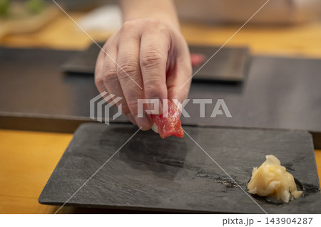 カウンター席に寿司を出す鮨職人の手元 カウンター席に寿司を出す鮨職人の手元 143904287