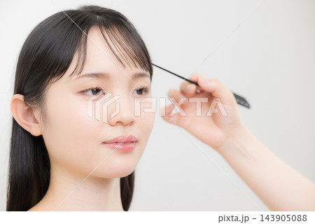 若い日本人女性の前髪をコームで整えるヘアメイクの手元、前髪のセット方法やヘアスタイリング 若い日本人女性の前髪をコームで整えるヘアメイクの手元、前髪のセット方法やヘアスタイリング 143905088