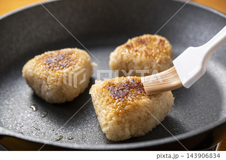 焼おにぎりに刷毛で醤油を塗る 143906834