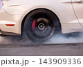 Car wheel burn rubber tire warming, Drag racing car burns rubber off its tires in preparation for race, Car burnout wheels tire with white smoke, Car wheel burnout with smoke from the spinning tire. 143909336