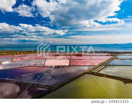 Salt extraction ponds divide the coastal landscape into colored basins beside the sea Salt extraction ponds divide the coastal landscape into colored basins beside the sea 143911123