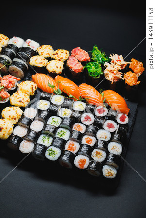 Assorted sushi rolls and nigiri arranged on a black platter for a meal 143911158
