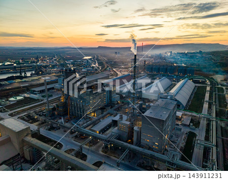 Industrial steel plant with smokestacks and processing buildings at sunset in a valley Industrial steel plant with smokestacks and processing buildings at sunset in a valley 143911231