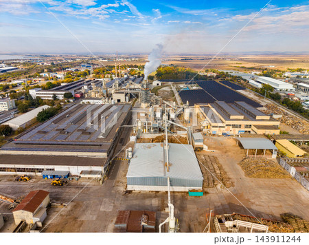 Industrial processing plant with smokestack and factory buildings in a rural area during daytime 143911244