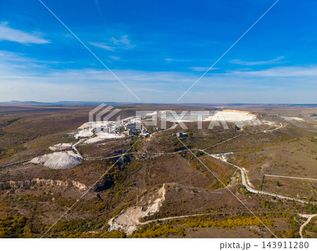 Aerial view of an open quarry with excavation areas, access roads, and surrounding land during the day 143911280