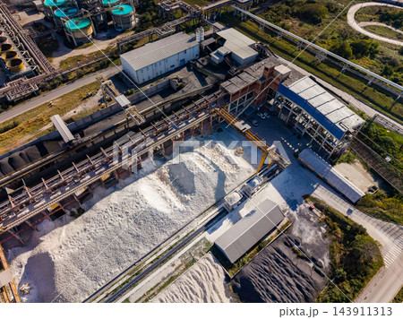 Aerial view of an industrial processing plant with storage piles and pipe systems during daylight 143911313
