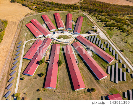 Aerial view of a poultry farm with red-roofed barns and rows of solar panels in a rural area Aerial view of a poultry farm with red-roofed barns and rows of solar panels in a rural area 143911399