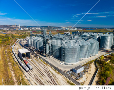 Rail lines and grain silos at an industrial storage terminal in a rural area during daytime Rail lines and grain silos at an industrial storage terminal in a rural area during daytime 143911425