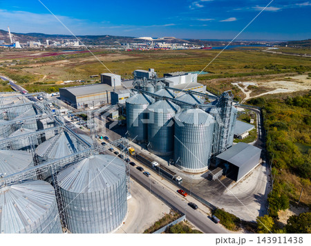 Grain storage silos and processing buildings beside a road in an industrial area during daytime 143911438