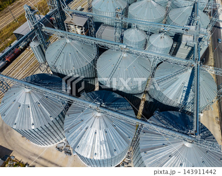 Aerial view of grain storage silos and conveyor structures at an agricultural facility during daylight 143911442