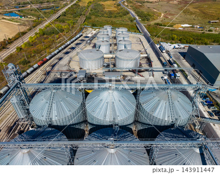 Aerial view of grain storage silos and rail lines at an industrial facility during the day 143911447