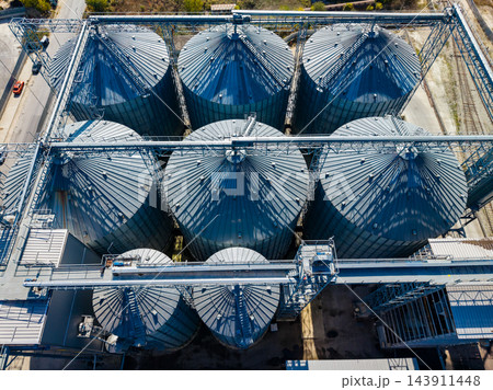 Aerial view of grain silos arranged in rows at an industrial storage facility during daytime 143911448