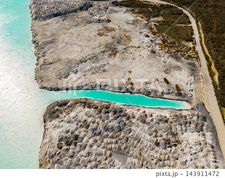 Chemical waste site with excavated ground and a turquoise runoff channel beside a waterway 143911472