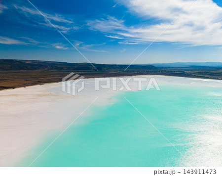 Chemical waste contaminates a turquoise water basin beside a pale shore under a cloudy sky Chemical waste contaminates a turquoise water basin beside a pale shore under a cloudy sky 143911473