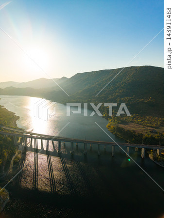 Railway bridge crossing a river between mountain slopes in evening sunlight Railway bridge crossing a river between mountain slopes in evening sunlight 143911488