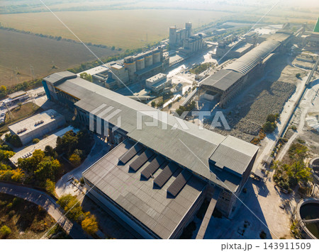Aerial view of an agricultural processing plant with grain storage buildings and fields during daylight 143911509