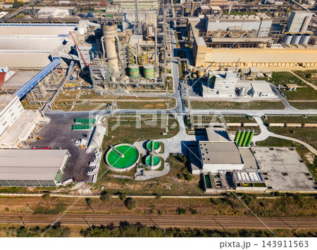 Aerial view of an industrial processing plant with storage tanks and roadways in operation during the day 143911563