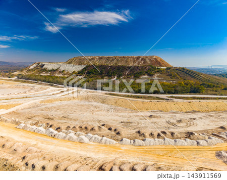 Open-pit mine with terraced earth and haul roads under a blue sky during daytime 143911569