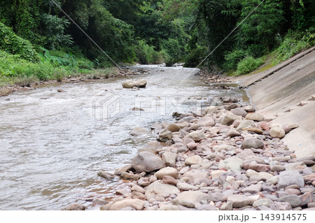 landscape of rapid wild river flowing through a lush green tropical forest. Riverbed and banks are covered with natural rocks and pebbles for travel in nature exploration and environmental in Thailand 143914575
