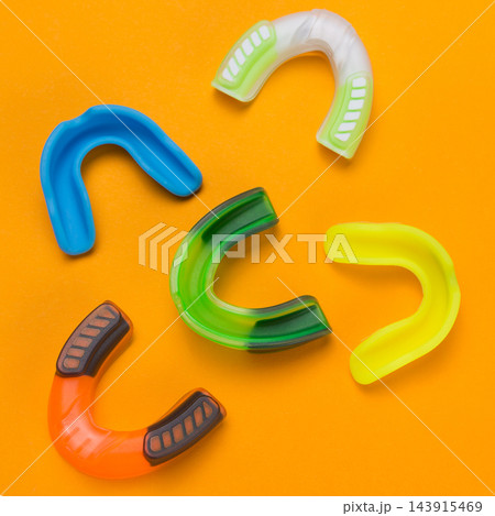 Colorful silicone sports mouthguards set on vibrant orange background concept Colorful silicone sports mouthguards set on vibrant orange background concept 143915469