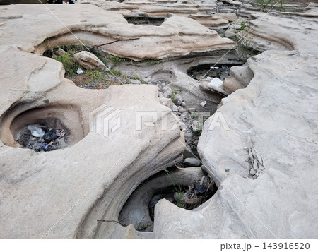 Natural rock erosion, sandstone craters, water basins, dry ground, organic formations, litter in some depressions. 143916520
