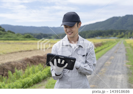 タブレットを持って農作物の様子を確認する農業従事者の男性 タブレットを持って農作物の様子を確認する農業従事者の男性 143918686