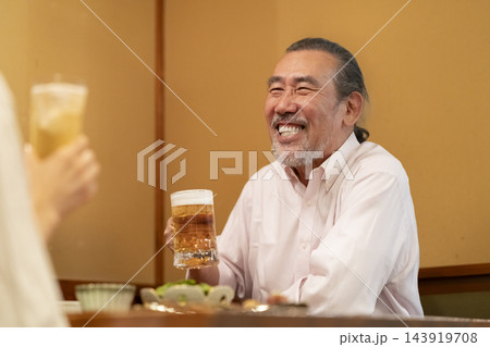居酒屋で生ビールを飲む笑顔のシニア男性 居酒屋で生ビールを飲む笑顔のシニア男性 143919708