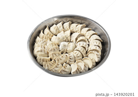 Tray of uncooked Chinese dumplings (jiaozi) arranged in a circular pattern on a white background 143920201