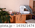 Sewing tools and materials on a desk near a sewing machine in a workspace 143921474