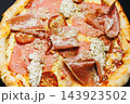 Pizza topped with tomato sauce, cheese, pepperoni, ham, and folded slices of cured meat 143923502