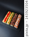 Four sushi rolls arranged on a black slate serving board for a meal 143923504