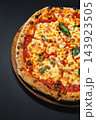 Margherita pizza with tomato sauce, melted cheese, and basil on a wooden board 143923505