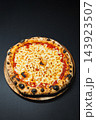 Round cheese pizza on a wooden serving board against a dark background 143923507