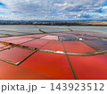 Salt extraction ponds spread across coastal flats near a city beneath a wide sky 143923512