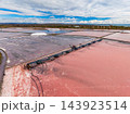 Salt extraction ponds and processing equipment spread across a coastal landscape under an open sky 143923514